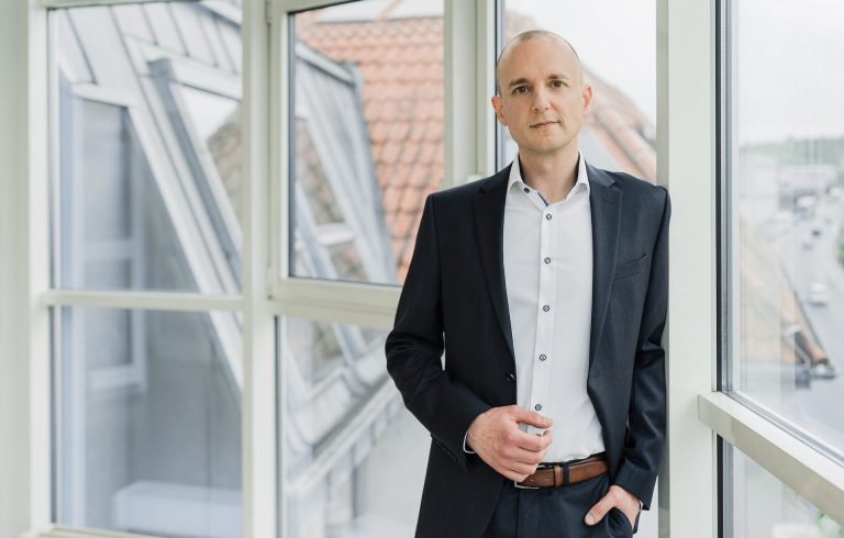 Porträtbild: Mario Schneider, Organisationsberater für das Gesundheits- und Sozialwesen, blickt freundlich in die Kamera